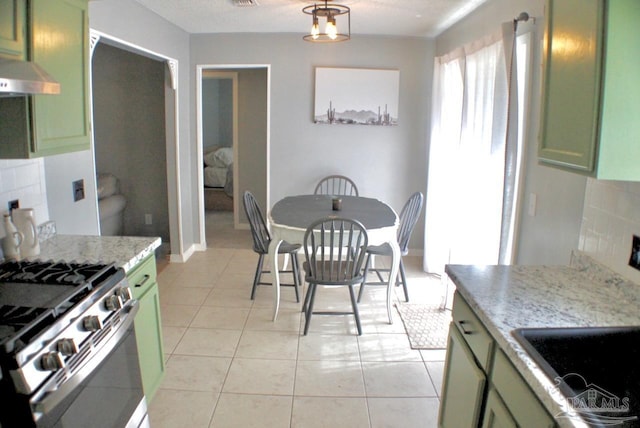 kitchen featuring light stone counters, green cabinetry, and stainless steel gas range