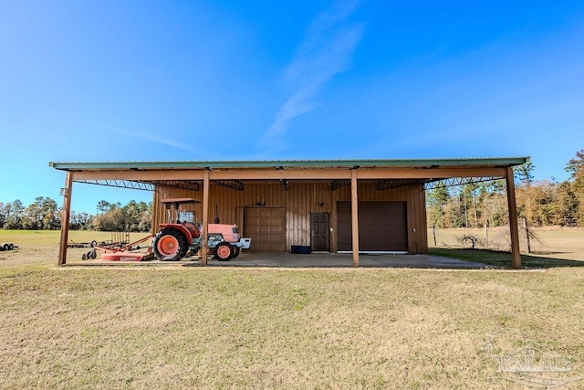 view of outdoor structure with a carport, a garage, and a yard