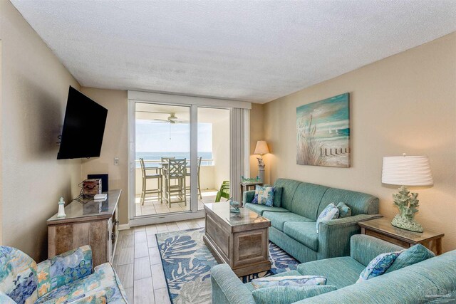 living area with wood finish floors, a textured ceiling, ceiling fan, and baseboards