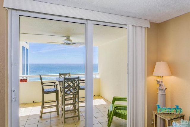 doorway featuring light tile patterned floors, ceiling fan, and a water view