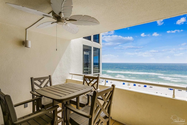 balcony featuring a beach view, a water view, and ceiling fan