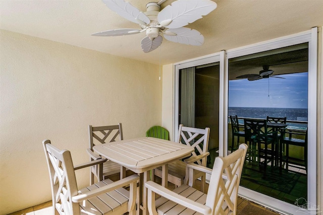 balcony featuring outdoor dining space, ceiling fan, and a water view
