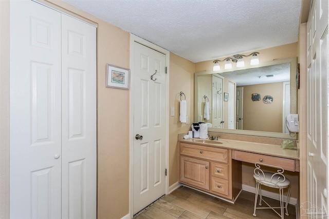 bathroom with wood finished floors, a closet, vanity, baseboards, and a textured ceiling