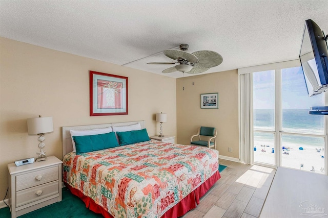 bedroom featuring a textured ceiling, a ceiling fan, wood finished floors, and baseboards