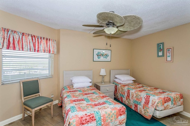 bedroom featuring baseboards, wood finished floors, and a textured ceiling