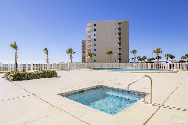 pool with a community hot tub, a patio area, and fence
