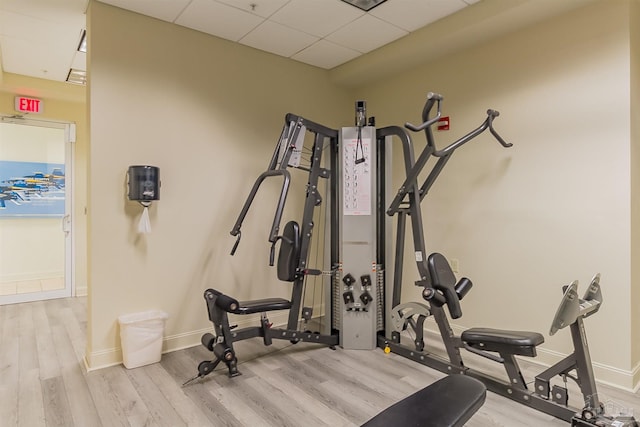 workout room with a paneled ceiling, wood finished floors, and baseboards