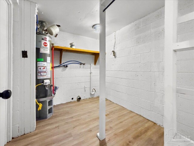 clothes washing area with gas water heater and wood-type flooring