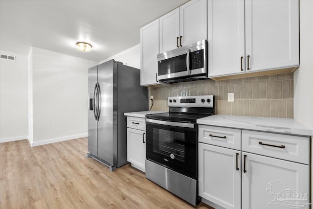 kitchen with decorative backsplash, appliances with stainless steel finishes, light stone counters, light hardwood / wood-style flooring, and white cabinetry