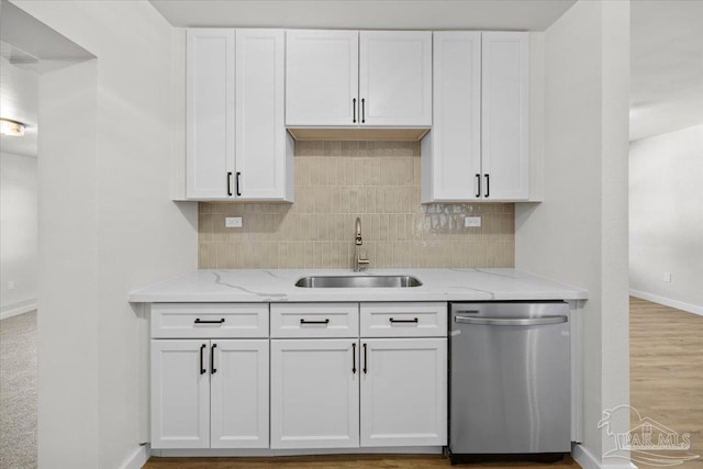 kitchen with light stone countertops, white cabinetry, sink, stainless steel dishwasher, and light wood-type flooring