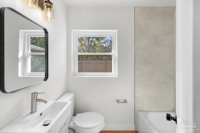 full bathroom with tiled shower / bath, toilet, a wealth of natural light, and sink