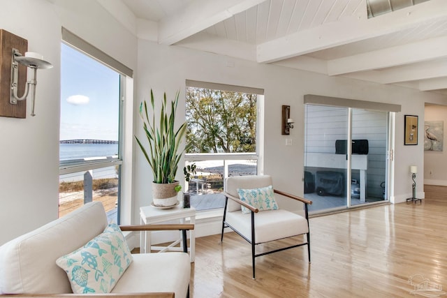 sitting room featuring light wood-style flooring, baseboards, and beamed ceiling