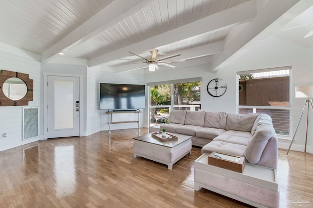 living area featuring light wood finished floors, visible vents, beamed ceiling, and ceiling fan