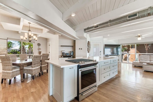 kitchen with stainless steel gas range oven, a healthy amount of sunlight, light wood finished floors, and a center island