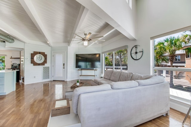 living area with beam ceiling, plenty of natural light, and light wood-type flooring