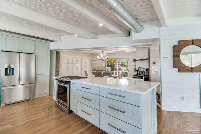 kitchen with wooden walls, light wood-style flooring, light countertops, appliances with stainless steel finishes, and a notable chandelier