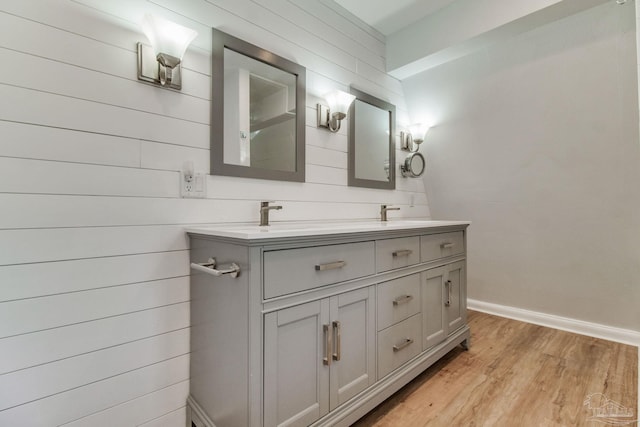 full bathroom with double vanity, baseboards, wood finished floors, and a sink