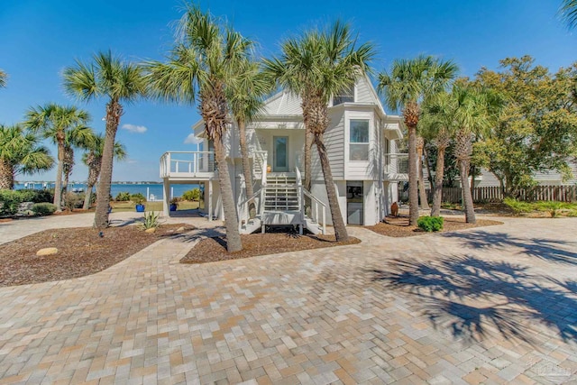 coastal home featuring stairway, covered porch, and driveway