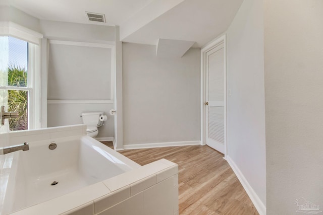 full bath with visible vents, baseboards, toilet, wood finished floors, and a bath