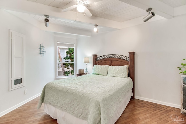 bedroom featuring ceiling fan, baseboards, beam ceiling, and wood finished floors