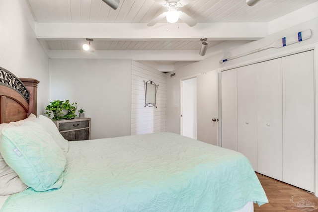 bedroom featuring ceiling fan, light wood-type flooring, beam ceiling, wooden ceiling, and a closet