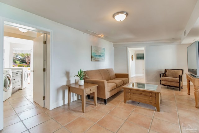 living room with light tile patterned floors, washing machine and dryer, and baseboards