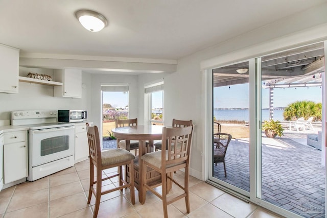 kitchen featuring white range with electric cooktop, stainless steel microwave, white cabinets, and light tile patterned floors