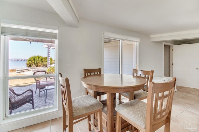 dining room with light tile patterned floors and a water view