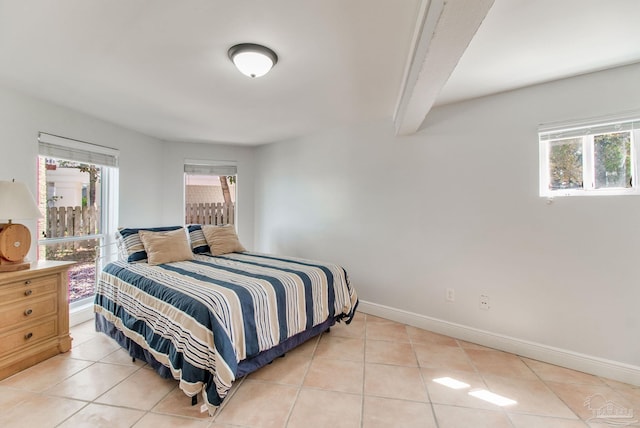 bedroom with beam ceiling, light tile patterned floors, and baseboards