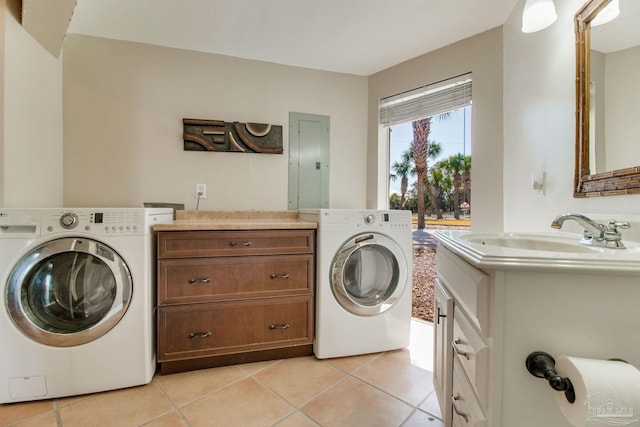 washroom with a sink, cabinet space, washing machine and dryer, and light tile patterned floors