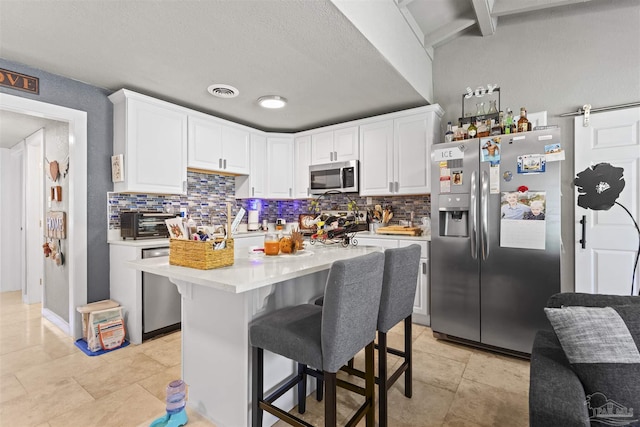 5607 Fairview Dr, Pensacola, FL 32505 - kitchen with stainless steel appliances, backsplash, light countertops, white cabinetry, and a textured ceiling