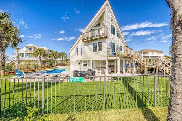 rear view of house featuring a yard, a balcony, a patio, and a covered pool