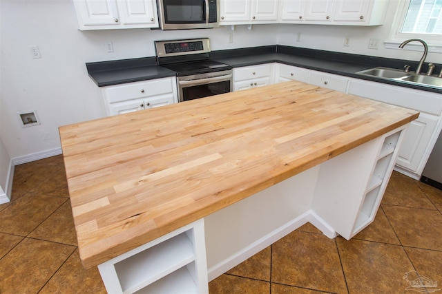 kitchen with appliances with stainless steel finishes, sink, white cabinets, and dark tile patterned flooring