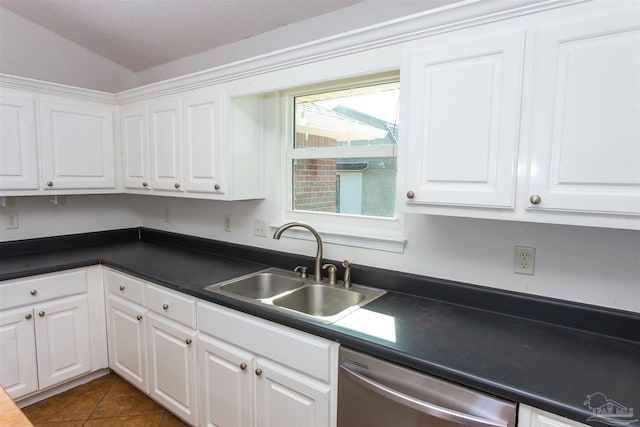 kitchen with dark tile patterned floors, dishwasher, sink, and white cabinets