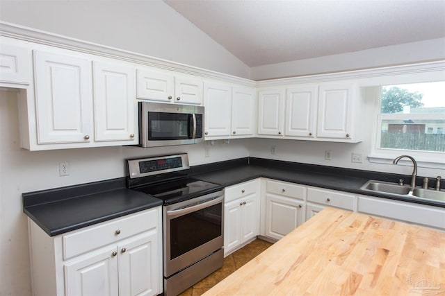 kitchen with lofted ceiling, sink, white cabinetry, stainless steel appliances, and tile patterned flooring