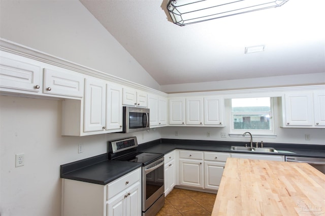 kitchen featuring sink, appliances with stainless steel finishes, white cabinets, vaulted ceiling, and tile patterned floors