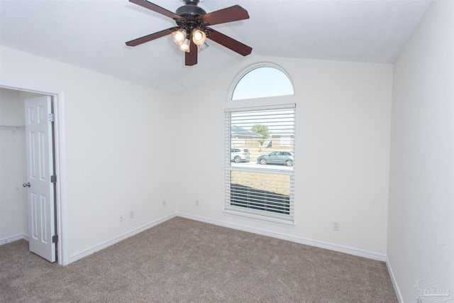 carpeted spare room with vaulted ceiling and ceiling fan