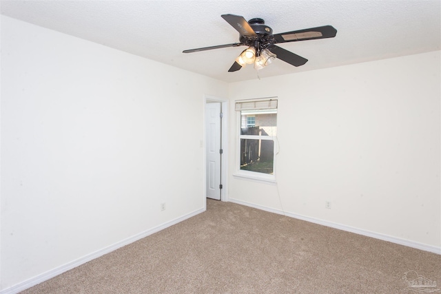 spare room featuring ceiling fan, light colored carpet, and a textured ceiling