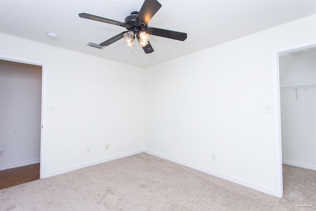 unfurnished bedroom featuring a spacious closet, light colored carpet, a closet, and a textured ceiling