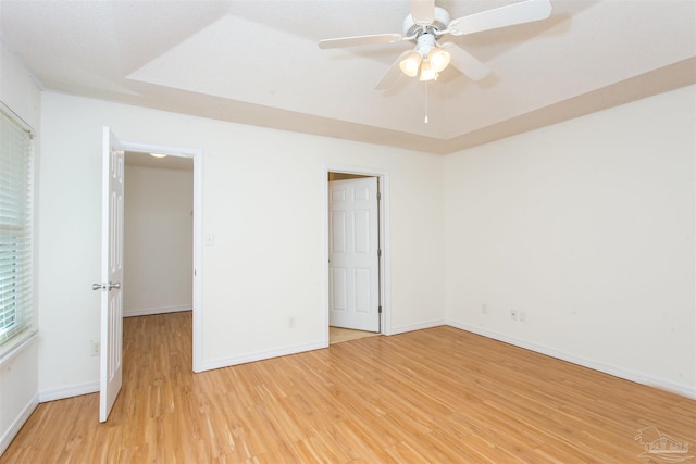 unfurnished bedroom featuring hardwood / wood-style floors, ceiling fan, and a tray ceiling