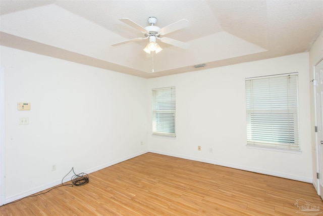 unfurnished room with wood-type flooring, a raised ceiling, and ceiling fan