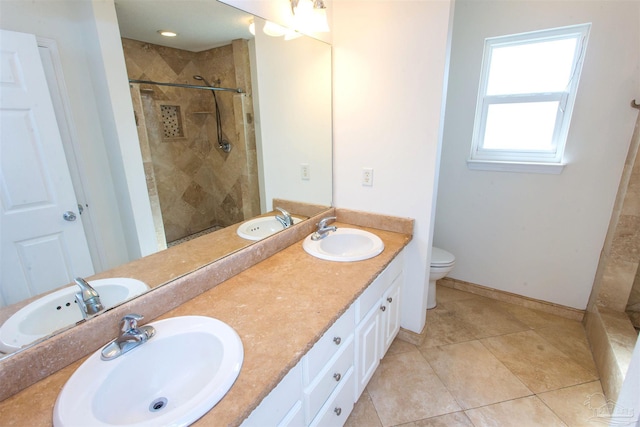 bathroom featuring vanity, tile patterned flooring, toilet, and tiled shower