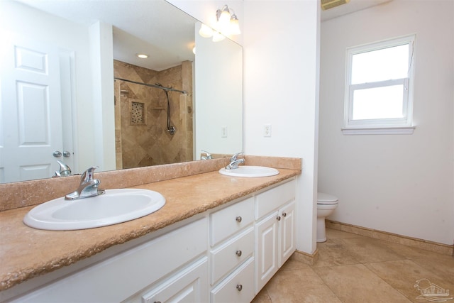 bathroom with vanity, toilet, tile patterned flooring, and a tile shower