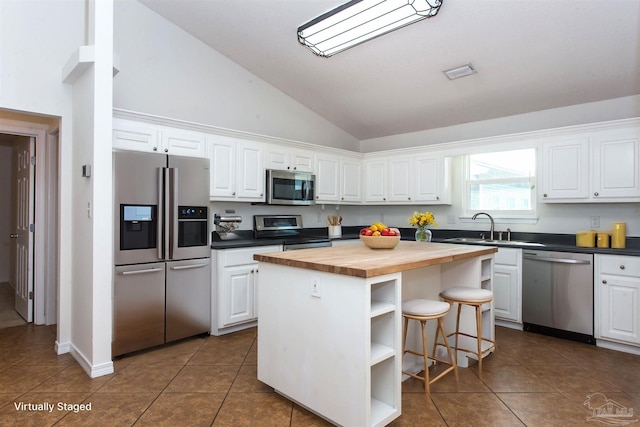 kitchen with sink, wooden counters, white cabinetry, stainless steel appliances, and a kitchen island