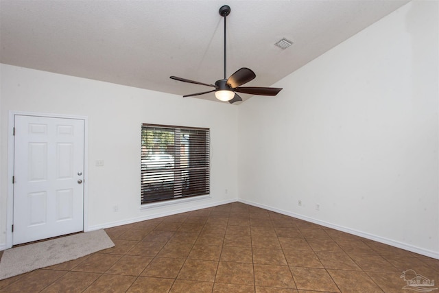 tiled empty room featuring ceiling fan, vaulted ceiling, and a textured ceiling