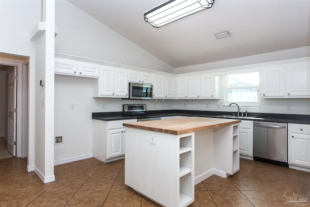 kitchen with appliances with stainless steel finishes, butcher block countertops, white cabinetry, sink, and a center island