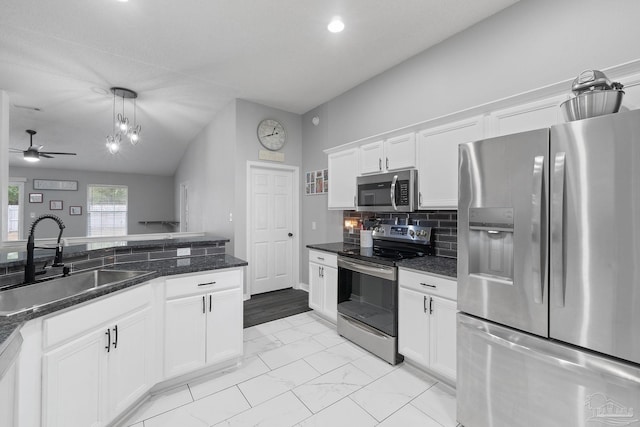 kitchen with white cabinetry, sink, dark stone countertops, hanging light fixtures, and stainless steel appliances