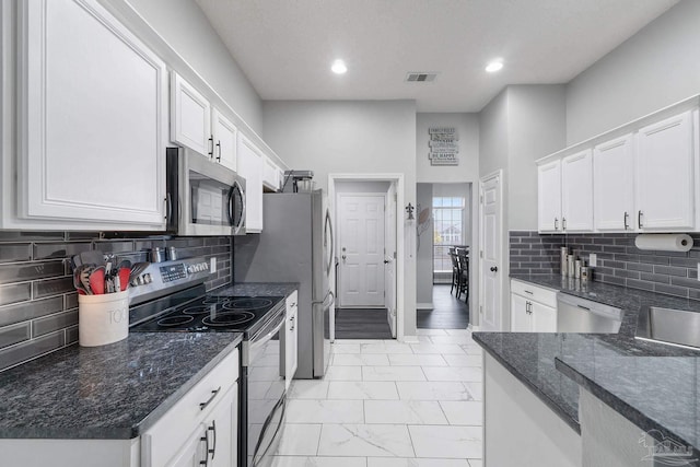 kitchen featuring white cabinetry, appliances with stainless steel finishes, backsplash, and dark stone counters