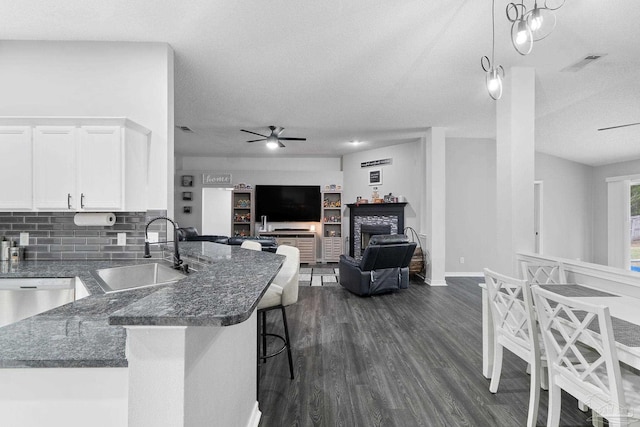 kitchen with sink, a breakfast bar, white cabinetry, dark stone countertops, and decorative light fixtures