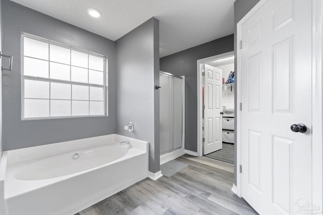 bathroom with plus walk in shower, hardwood / wood-style floors, and a textured ceiling